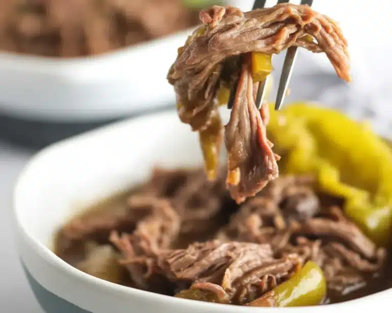 Delicious one-pot Italian beef topped with cheesy garlic bread bombs in a rustic kitchen setting.