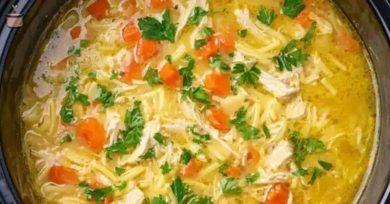 Creamy chicken noodle soup in a bowl, garnished with fresh herbs.