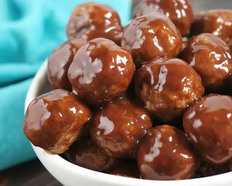 Hot honey meatballs simmering in a crock pot with a sweet and spicy sauce.
