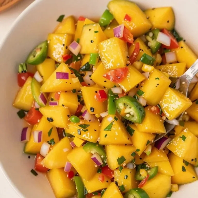 Fresh mango salsa in a bowl with cilantro, jalapeños, and lime wedges